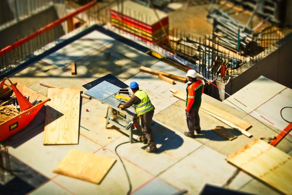 Photo d'un chantier avec deux ouvriers qui coupent du bois.