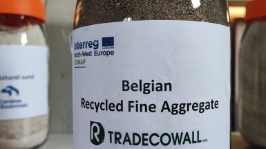 Focus sur un pot avec une étiquette où il est écrit : Belgian Recycled Fine Aggregate" par TRADECOWALL.