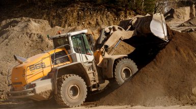 Un tracteur pelleteuse ramasse de la terre sur un chantier.