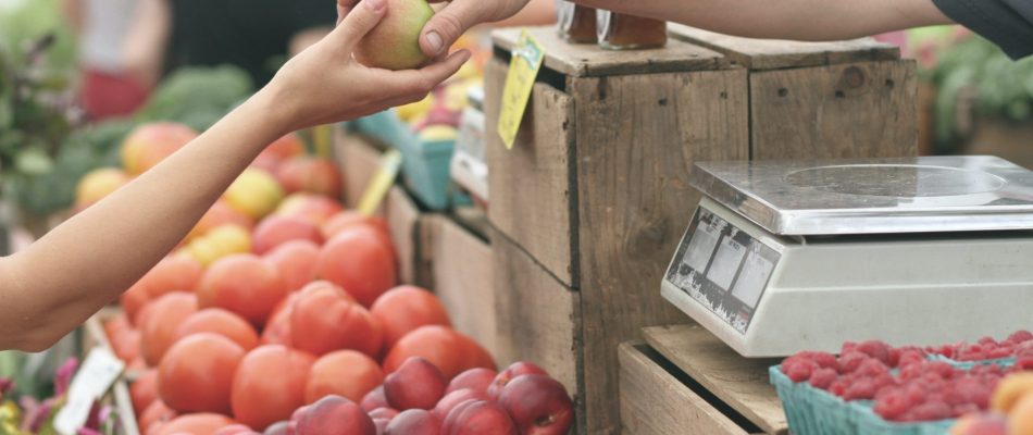 Photo illustrative d'un commerçant qui vend un fruit à un consommateur sur un marché.