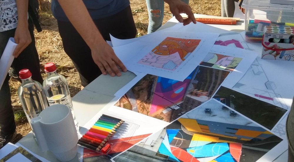 Groupe autour d'une table à l'extérieur où est disposées plusieurs feuilles et photos.